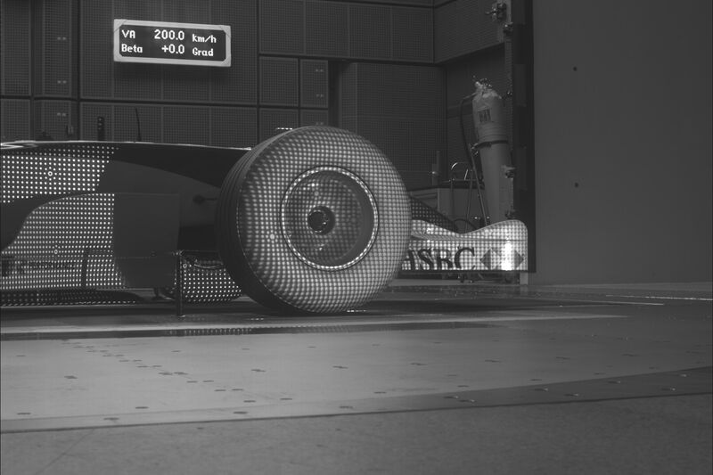 Formula 1 car in a wind tunnel with a projected target pattern on the tire